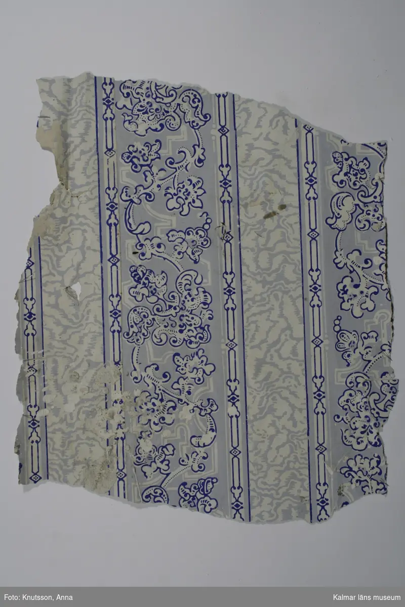 KLM 12538:4. Tapet av papper. Tryckt tapet med lodräta mönsterindelningar med ranka (akantusmönster) i ultramarinblått, vitt och ljusblått. Datering: 1840-1860-tal.