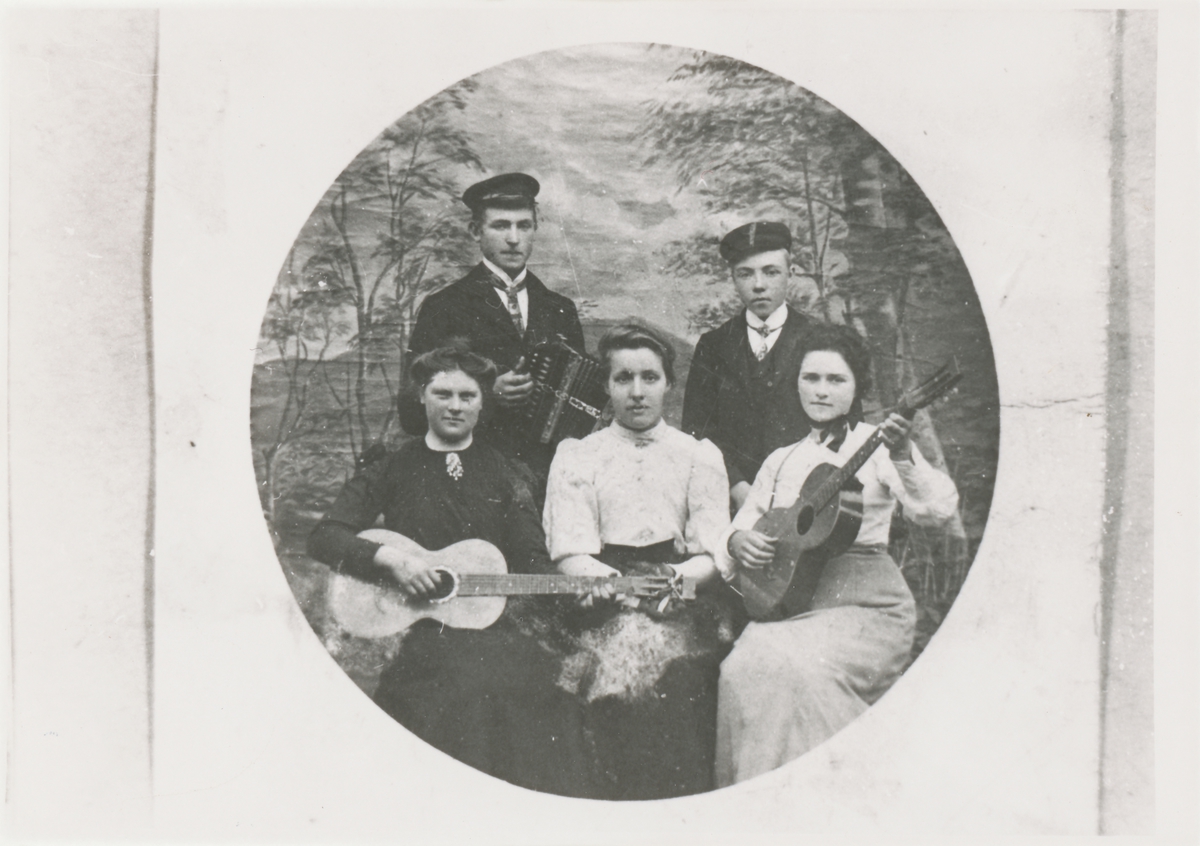 Gruppeportrett i fotostudio av fem personer. To har gitar i hendene, en har trekkspill.