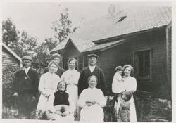 Familiebilde utenfor et hus med 5 kvinner, 3 menn og 2 barn.