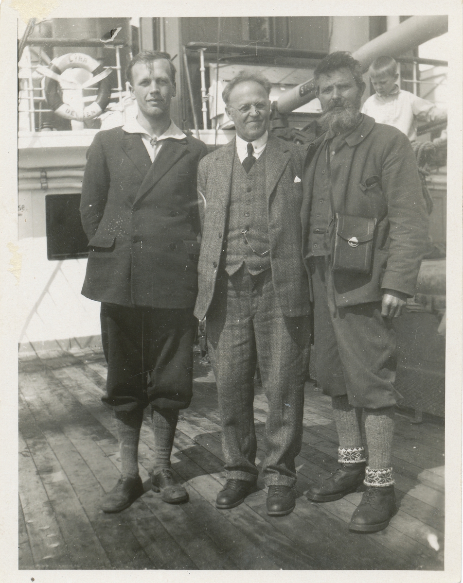 Gruppeportrett av tre menn og en gutt ombord i båten "Lyra" fra Bergen.