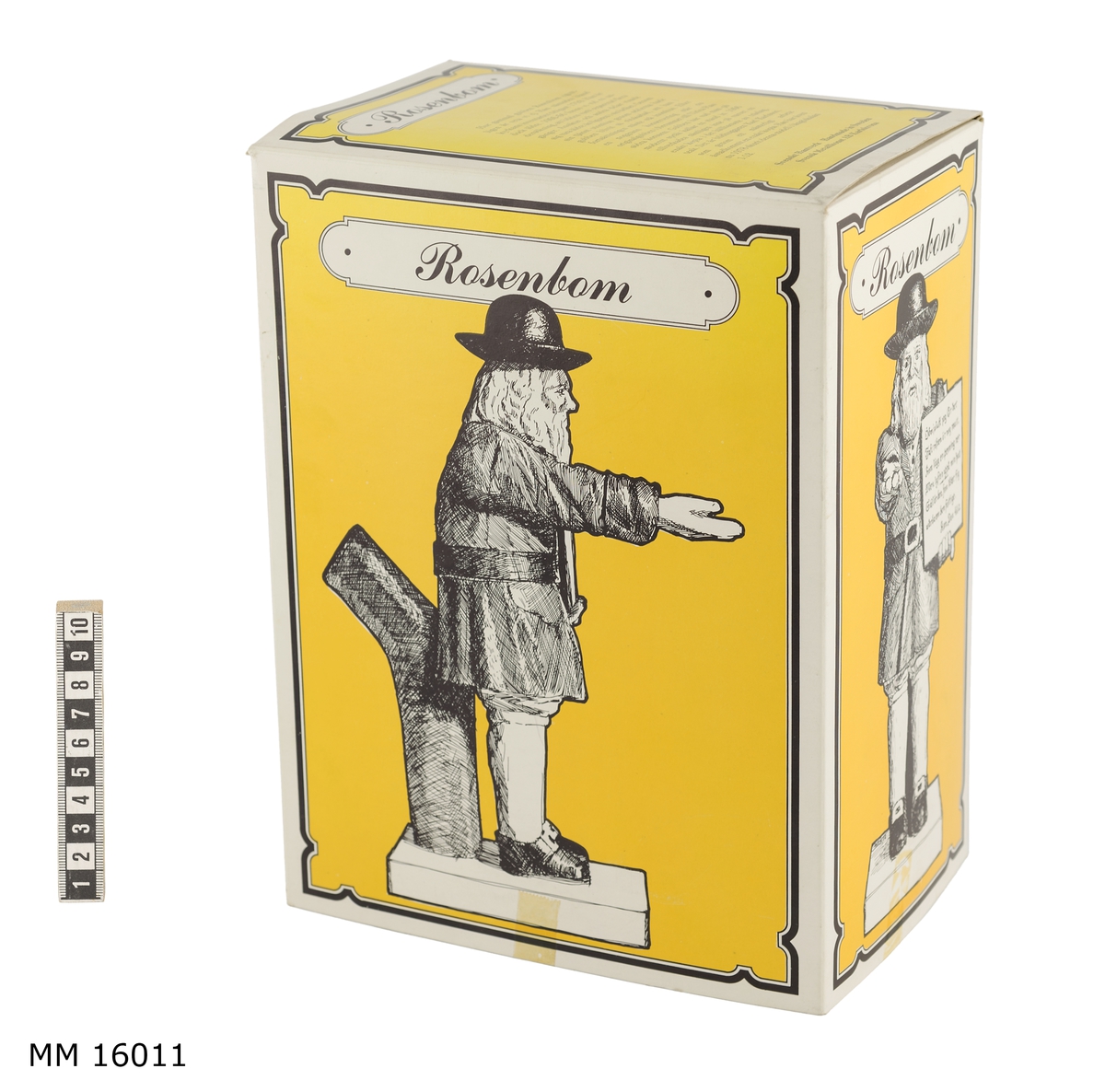 Gjuten modell av gubben Rosenbom i skala 1:12.

På grå sockel och vilande mot en trästock, står i 1750-talskläder, helfigur, en man med utsträckt högerarm. Tiggarpåsen på högra axel med ett textplakat i handen. Ansiktet vänt rakt framåt. Kläderna består av: svarta skor med gula spännen, grå strumpor, gula knäbyxor, rödbrun lårlång rock med svart bälte och gult spänne. Svart stor hatt med bälte. Axellångt hår och skägg är grått.