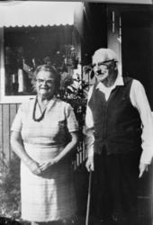 Eldre mann og kvinne, ektepar?, utenfor huset på trappa, i U