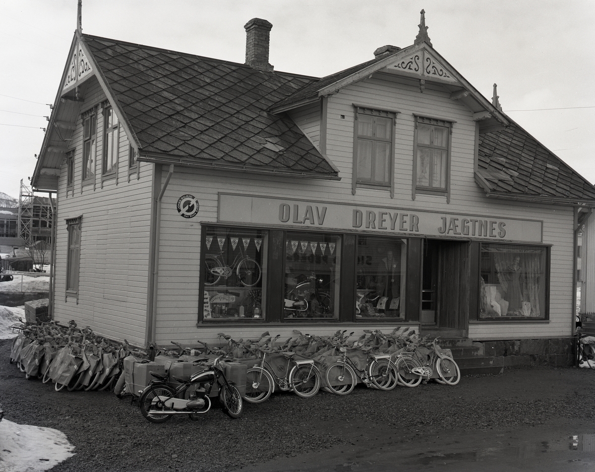 Olav Dreyer Jægtnes' butikk i Strandgata på Sortland 1955. På veggen er reklame for Jonas Øglænd - Den Beste Sykkel. I bakgrunnen til venstre kan skimtes rådhuset, som er under bygging.

Samme bilde som MNSF0123-046.