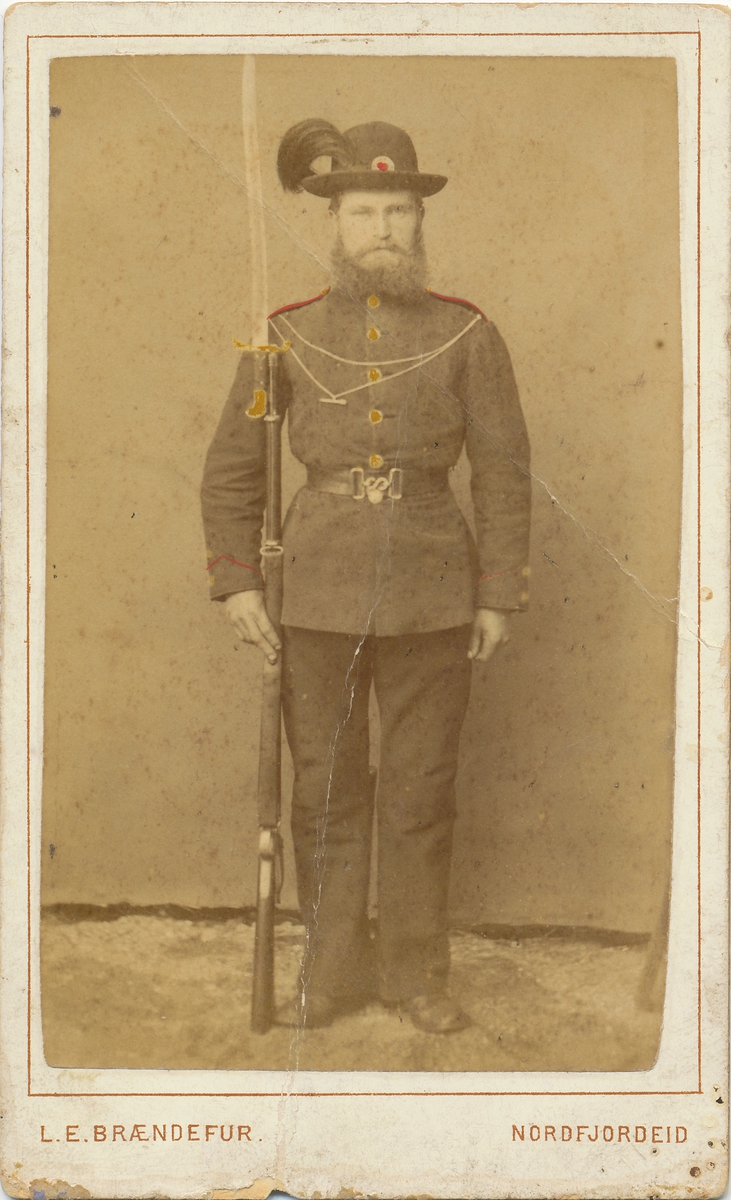 Portrett av en mann i militæruniform og våpen i handa.