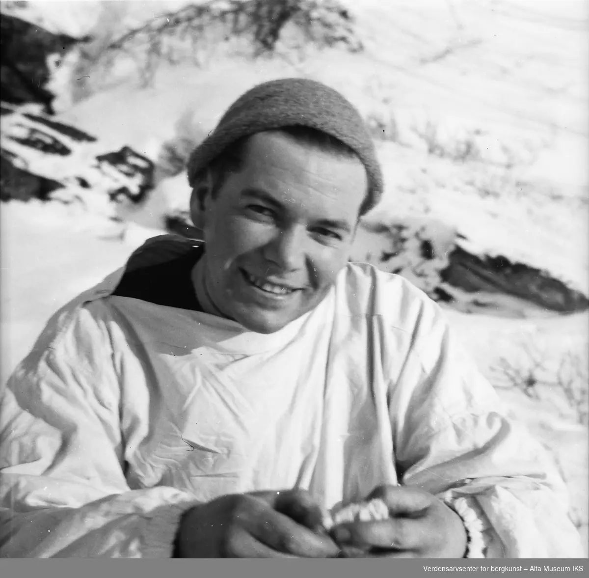 En ung mann i vinterklær smiler til kameraet.