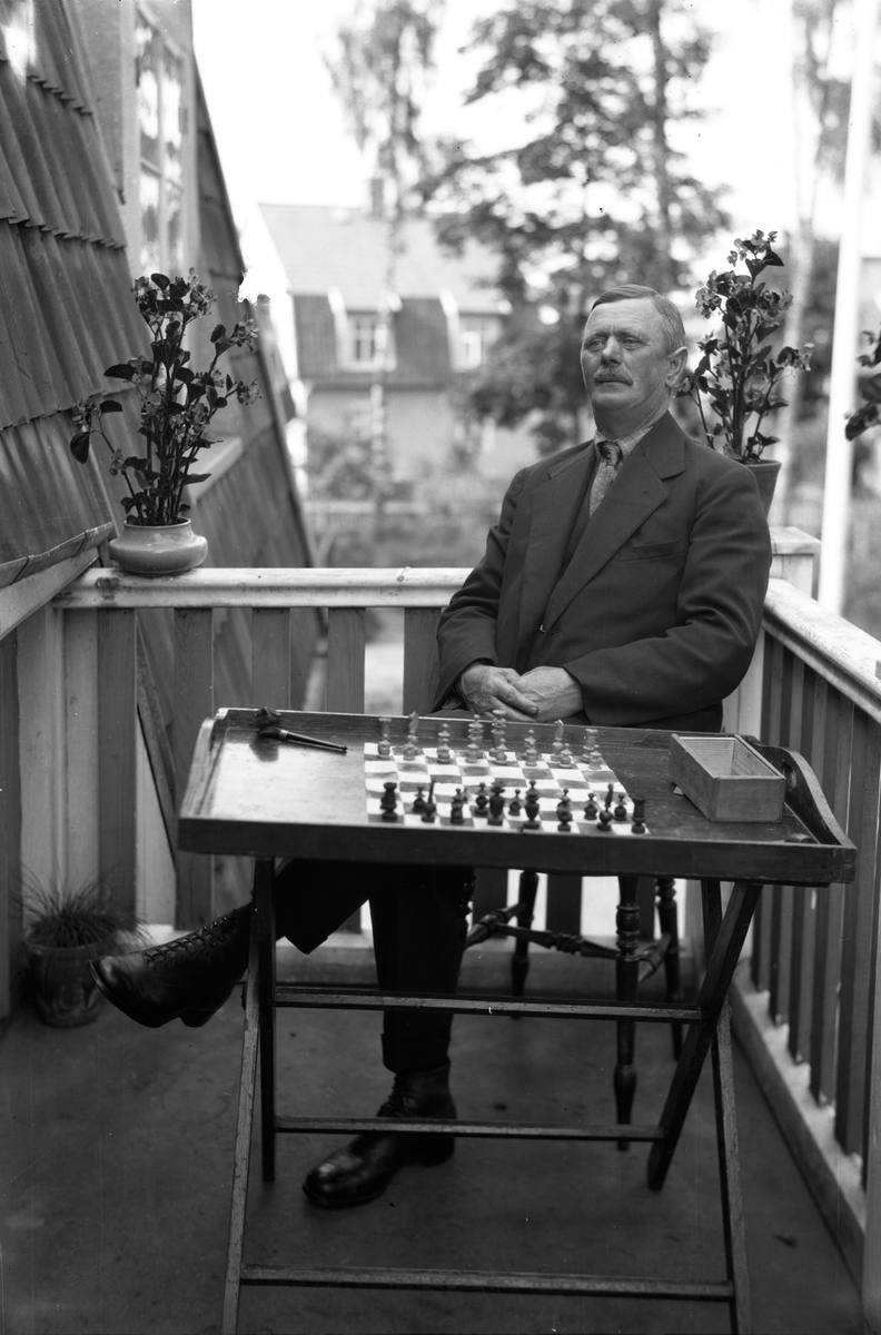 Ernst Holmgren sitter på sin balkong på Presidentgatan 23 i Jönköping. På bordet bredvid sig har han ett schackbräde. Han föddes 6/3 1873 och fick sju barn. 
Han arbetade först som grovarbetare, därefter som stensättare, 
var bl.a. med och byggde teatern. 
Han hade sju barn.
Han brukade sjunga och joddla på gatorna.