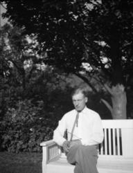 Fotosamling etter Cappelen. Mann som sitter på en benk fotog