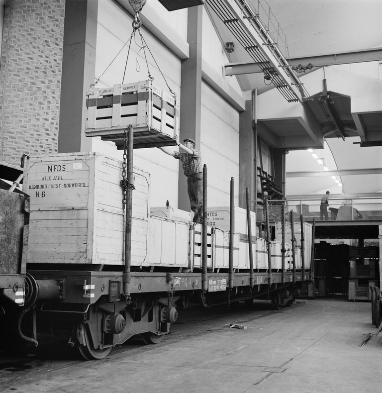 Jernbanevogn blir lastet med trekasser fyllt med reservedeler for produkter fra Kvernelands Fabrikk AS, som er i bruk i England. Skjæveland laster vognen.