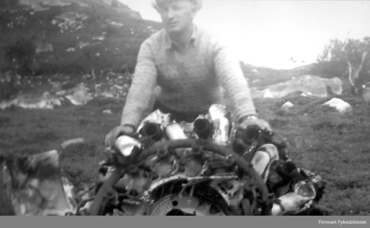 Nils Klaussen holder opp vrakrester av et fly. Bildet er tatt ved Jarfjord/Kirkenes ca. 1952/53. Rester av et flyvrak lå strødd rundt i området. Ifølge Inger-Lill Knutsen var disse restene etter et russisk fly som ble skutt ned i området under krigen.