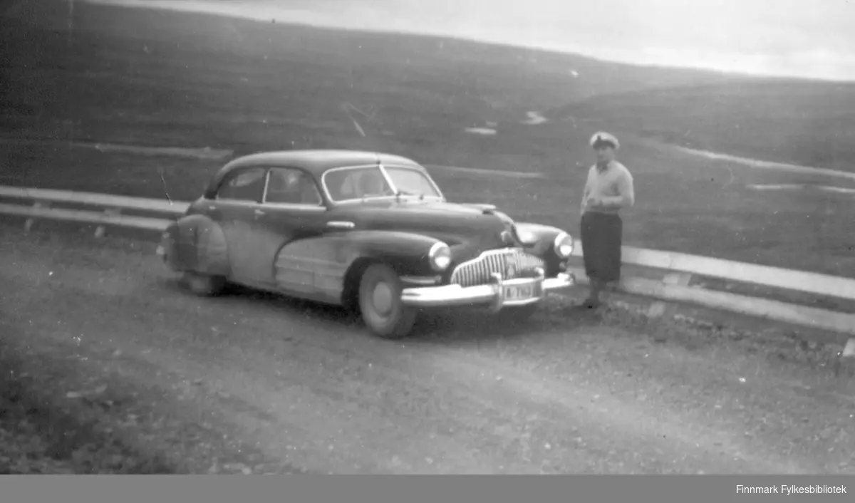 Nils Klaussen står ved en bil Buick (1942) med registerskilt A-7163 et sted på Finnmarksvidda. Bildet er tatt i forbindelse med en tur familien var på i Finnmark i 1952 eller 1953.