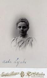 Kvinne i halvfigur, kledd i lys kjole/bluse med puffermer. K