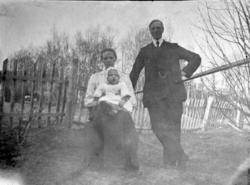 Portrettbilde, tre personer ved gjerde i hagen i Anset?, man