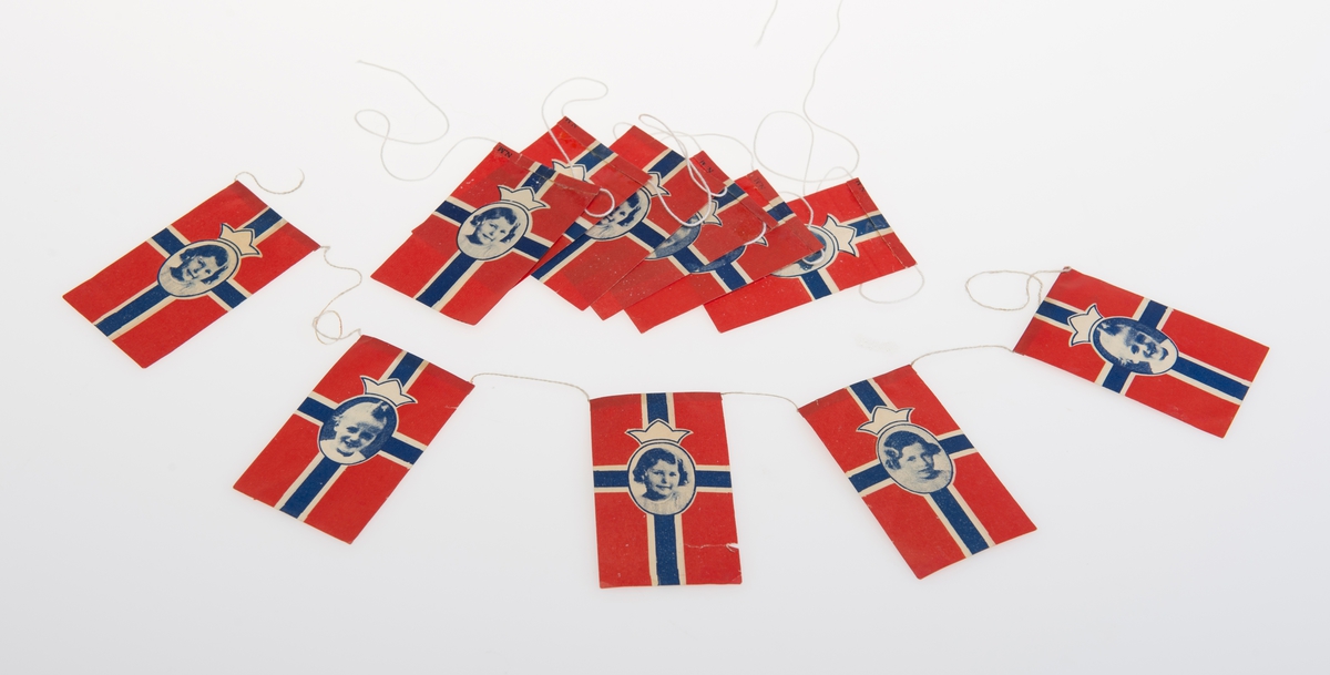 Norske Flagg dekorert med bilder av kongebarna: Prins Harald, Prinsesse Ragnhild Prinsesse Astrid som barn.
Flaggene henger sammen med bomullstråd
Er i to deler, sannsynligvis har det vært en sammenhengende rekke.