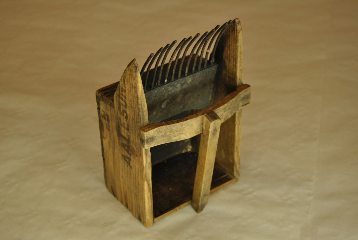 Bærplukker i tre med jerntenner. Med håndtak. Lagd av margarinkasse fra Aalesund.