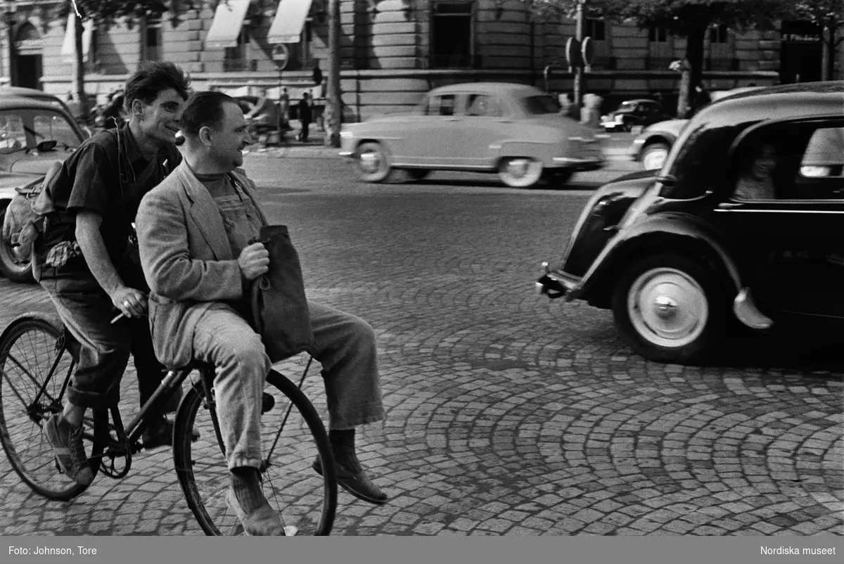 Paris. Två män på cykel, biltrafik i bakgrunden.