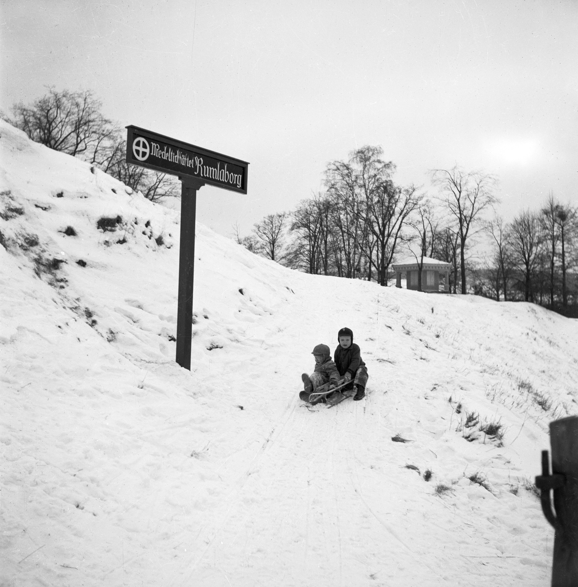Två barn leker med en kälke i snön vid Rumlaborg i Huskvarna.