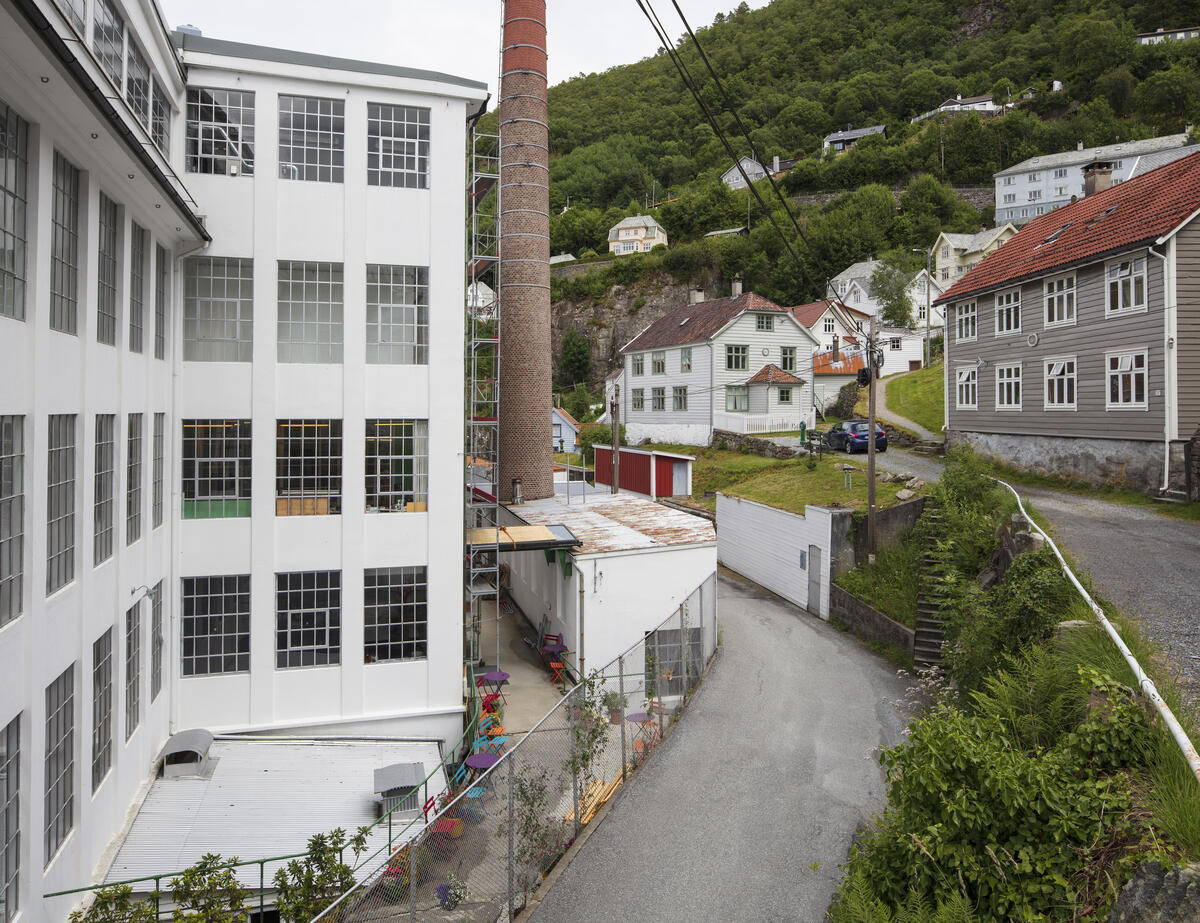 Bygda Salhus utanfor Bergen, med den tidlegare tekstilfabrikken Salhus Tricotagefabrik, fabrikkpipa og ein arbeidarbustadtil høgre. (Foto/Photo)