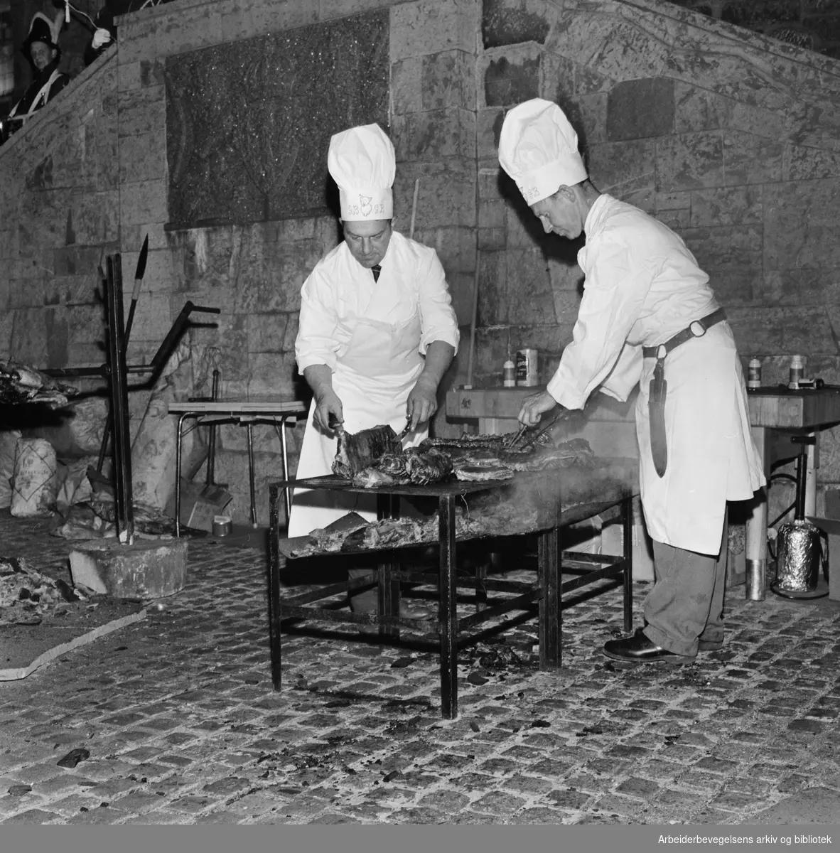 Foreningen Akershus Slotts venner markerer 10 års-jubileum med festmiddag i slottssalen. Kokkene Bruno Gjerdrum (t.v.) og Gunnar Bjerke tilbereder maten i borggården. 27. September 1961.