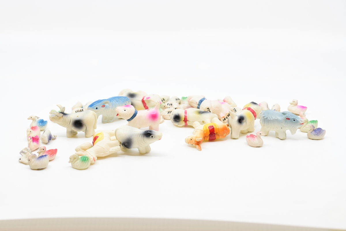 En samling små plastdyr som er støpt og påmalt farge og detaljer som halsbånd, øyne, ører og lignende. Det er 43 små fugler med noe ulik utforming og farger. Videre er det to geiter, to esler, to bulldogger, to hunder, en katt, en tapir(?) og en okse med horn. I alt er det 54 plastdyr.