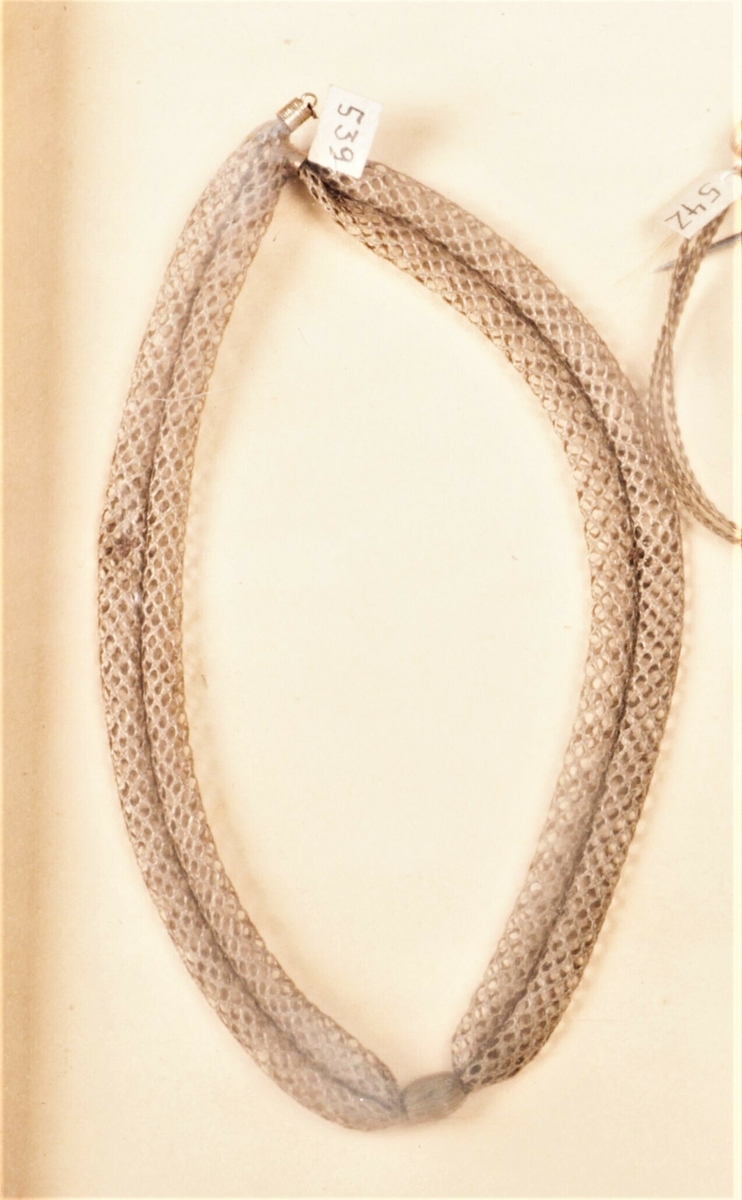 Halsbånd av to rader fint flettverk og en kule på midten. Holdes sammen med en fin gullås.