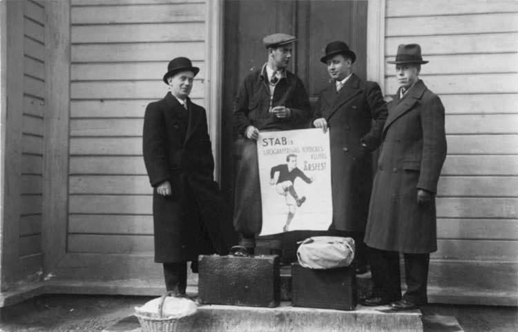Fyra män håller i en affisch med texten: STAB:s Litografernas fotbollsklubbs Årsfest.