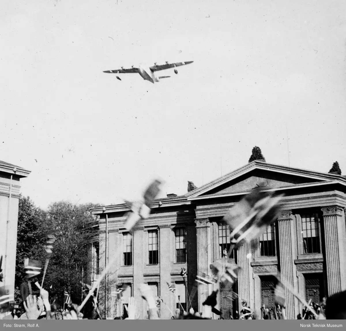 Fly over menneskemengde veivende med flagg på Universitetsplassen, Oslo, mai 1945,