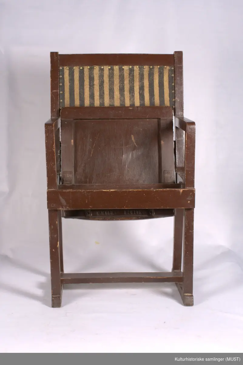 Klappstol, brunmalt. Setet har sekundært trekk av voksduk. Ryggen har stripet trekk med pyntenagler.
Stol med ermlener, stofftrukket rygg i brunt og svartstripet stoff. Klappsetet trukket med rød-hvit og blårutet plastduk. Setet hengslet på en tverrgående stokk i stolen. Klappstolen har vært en i en rekke (i hvert fall satt sammen to og to).