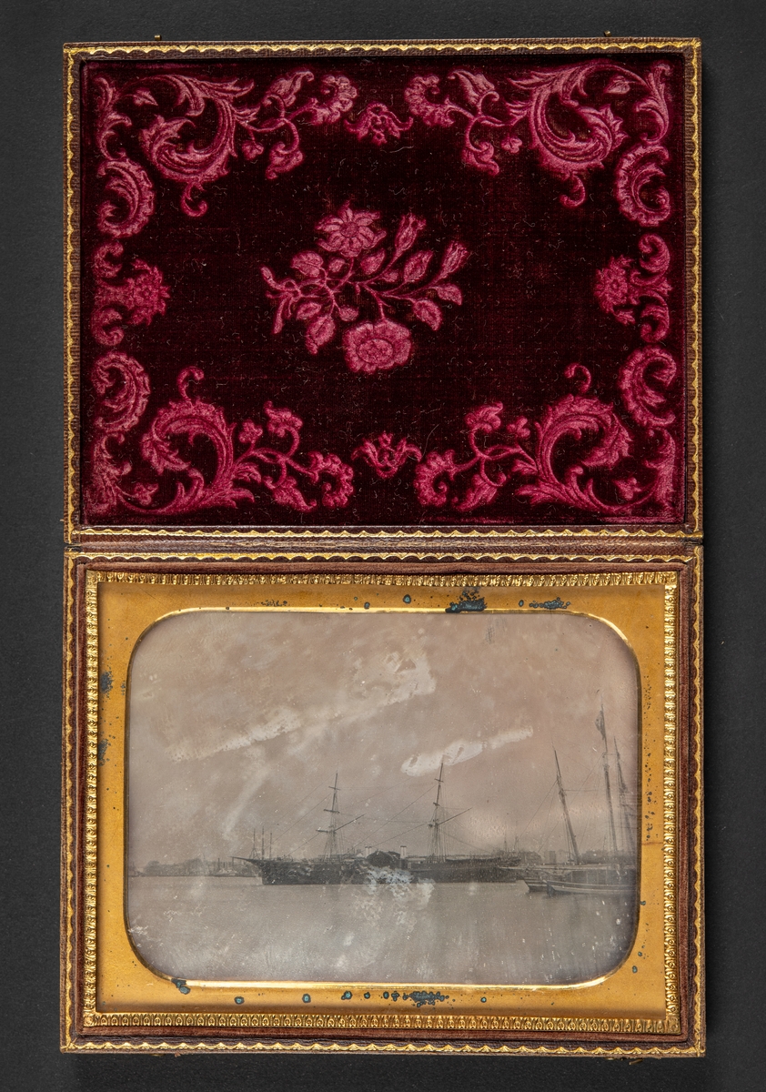 Daguerreotypi, föreställande varmluftsskeppet John Ericsson, infattad i ett läderetui med ornamentering. Locket fodrat med mönstrad röd silkessammet.