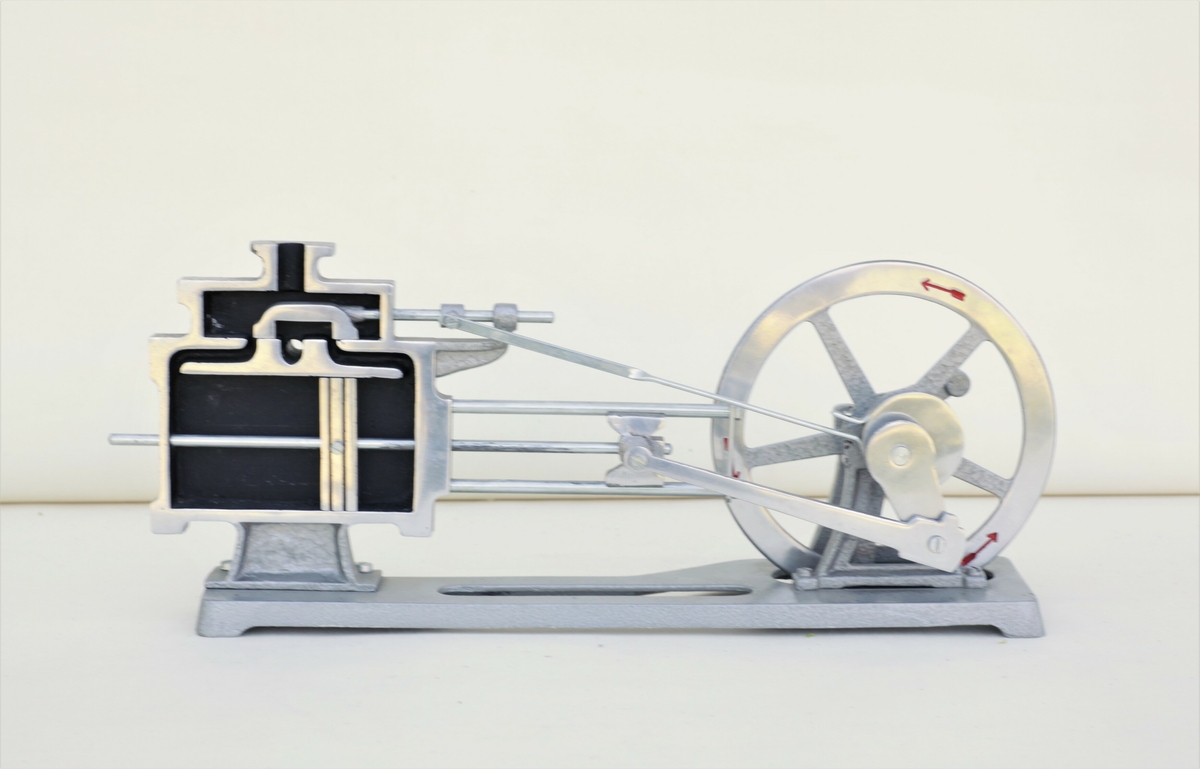 Gjennomskåret modell av dampmaskin med svinghjul.