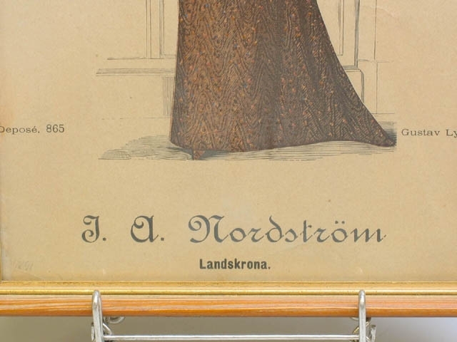 Två modeplanscher från J.A. Nordström, Landskrona. Föreställer kvinnor i sent 1800-tals mode av Gustav Lyon. Planscherna är inramade i guldmålade träramar. Klistermärke baktill med text "EKLUNDS KONST, LANDSKRONA. MODERNA INRAMNINGAR TEL. 10259, TEL 11083".