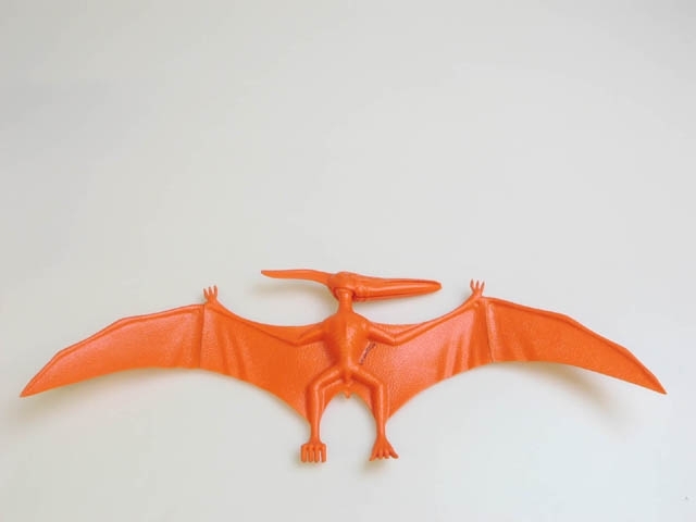 Plastmodell av en flygande dinosaurie - "FLYING REPTILE (PTERANODON)". Modellen är orange och ihopsatt. Man sätter ihop modellen utan lim. Till modellen hör också en orange modell av en klippa som dinosaurien skall stå på samt en extra vinge. Ligger i originalkartong med bilder på dinosaurien och information på engelska.
Mått: kartong: H 16,5, B 15,7, Dj 10,4 cm. modell: H 16,2, B 45,8 cm, klippa: H 7,5, B 10, L 12,7 cm, vinge L 16, B 6 cm.