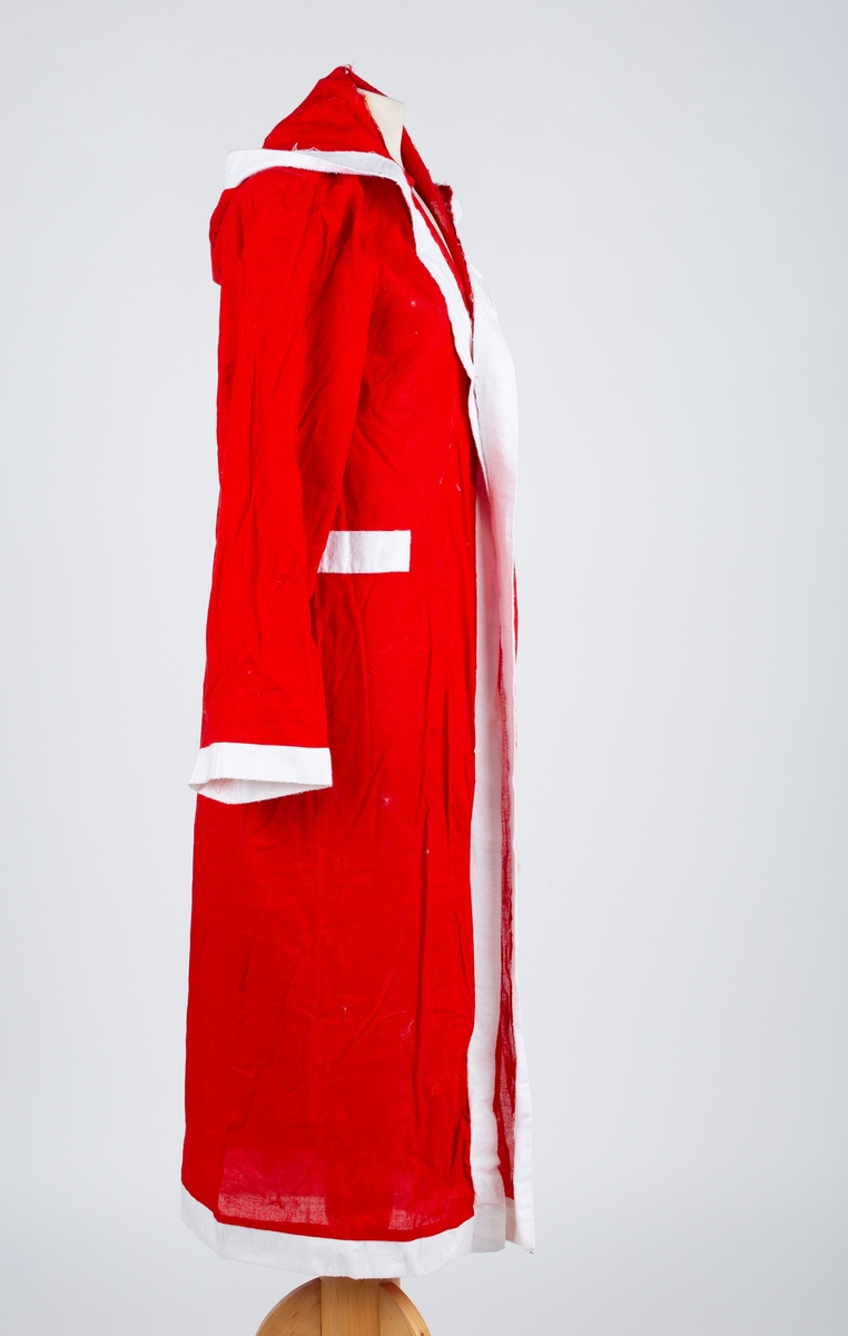 Julenissedrakt i bomull og syntetisk materiale, lang rød frakk med hette, kantet med hvitt stoff, med tilhørende hjemmelaget hvitt skjegg. Snor til belte. Voksen størrelse.