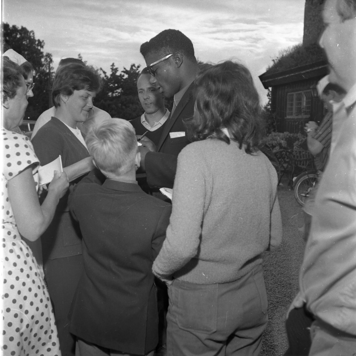 Boxaren Floyd Patterson i solglasögon omgiven av en folksamling som han skriver autografer åt. De befinner sig vid Gyllene Uttern strax söder om Gränna.