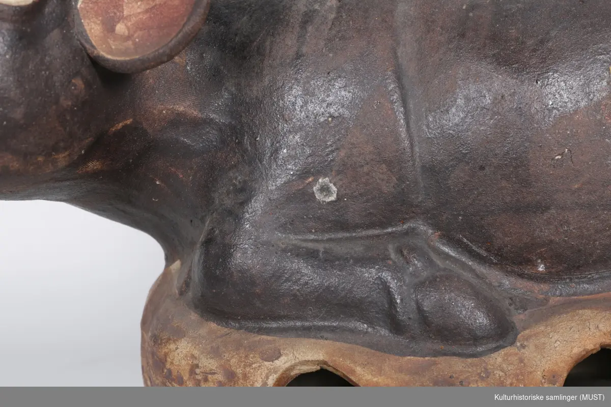 Oksen har store horn,og ser ut til å røyte.  Den har en mann sittende på ryggen.