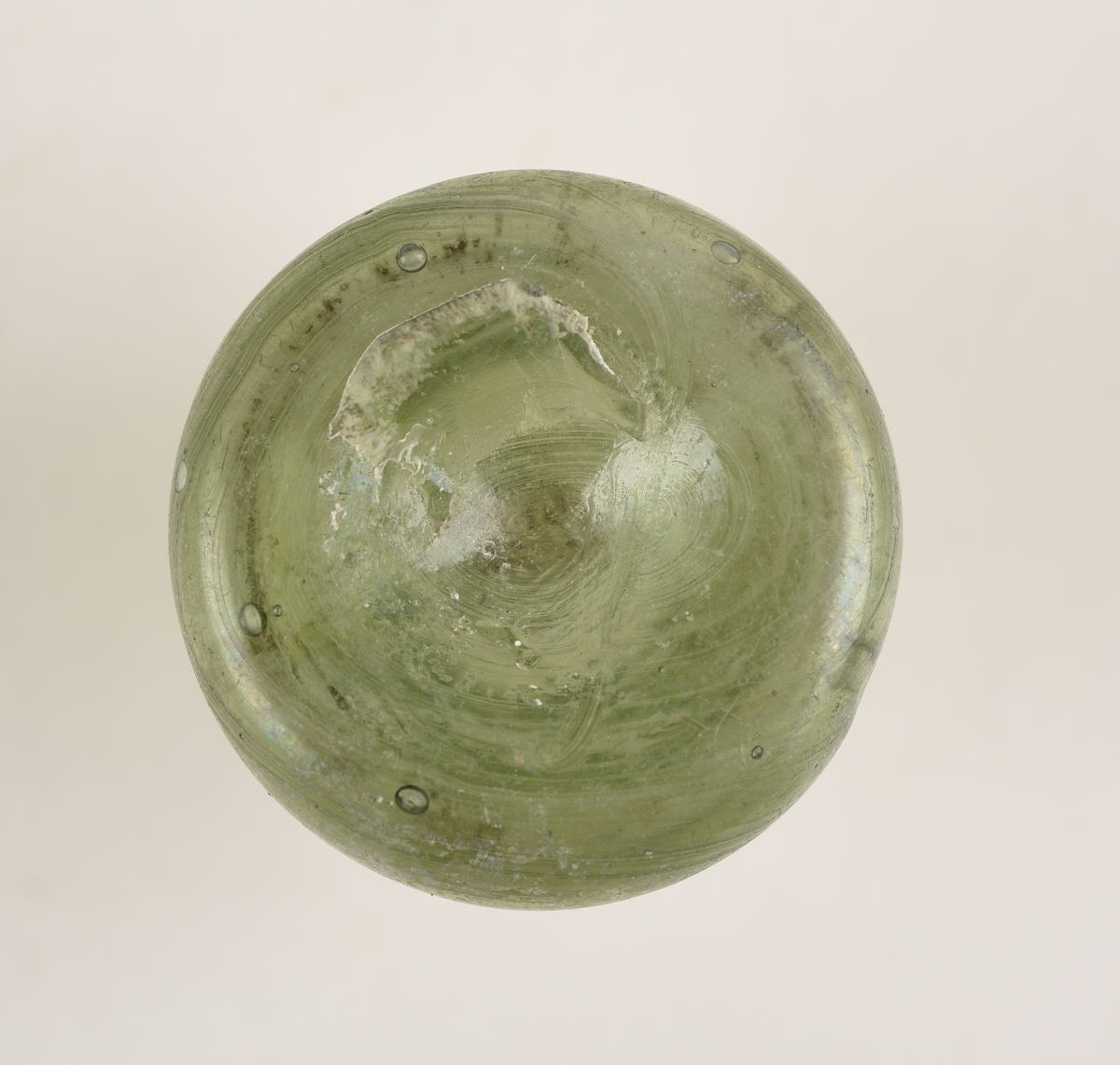 Sylindriskformet glassflaske. Deler av randen mangler. På toppen av flasken er det et sirkelformet hull. Hullet har en diameter på 1,2 cm. Flasken er lys grønn i farge.
