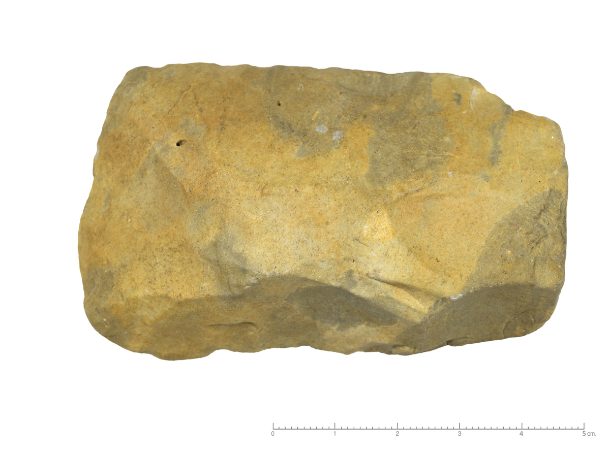 Neolittisk tosidig øks, ev. mesolittisk kjerneøks, symmetrisk tilhugget, uten tydelig eggfasett. Nakken ender i en stump flate. Undersiden er flat, tverrsnittet hvelvet. Bruksskader i eggen, gul patina. 


