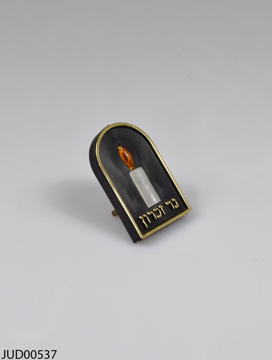 Årslampa (yahrzeit-lampa). Stickkontakt med lampa i form av ett stearinljus och hebreisk text i guld.