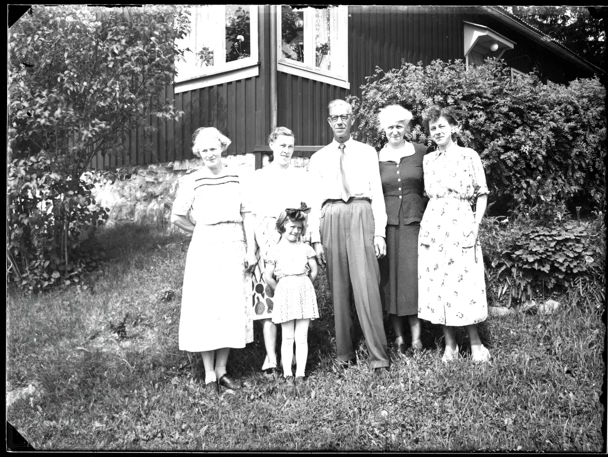 En gruppe på fem står samlet i en hage utenfor et hus, familien Nesset på Jaren