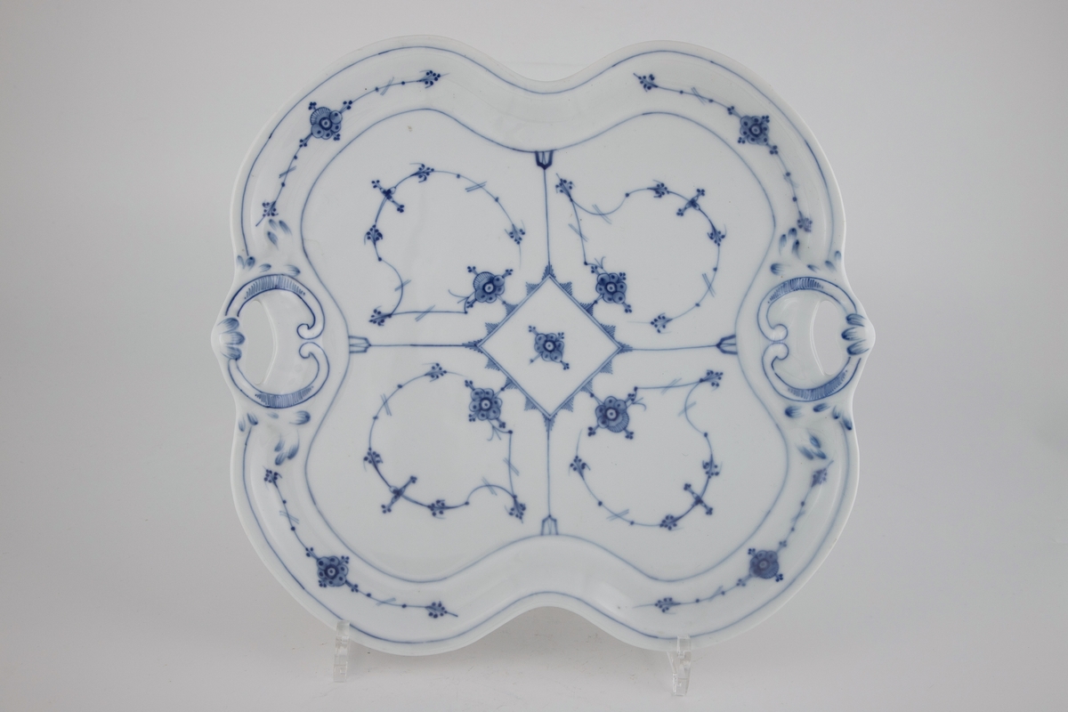 Kvadratisk fat i glasert porselen med mykt avrundede hjørner samt to hanker. Oversiden er dekorert med koboltblå underglasurmaling i form av stråmønster. Undersiden av fatet er uglasert.