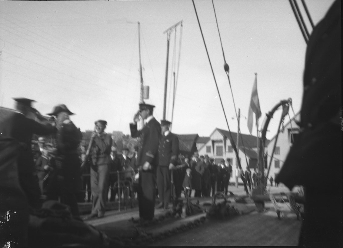 Möjligen ombord på kanonbåten HMS Svensksund. Officerare gör honnör. Folk på kajen.