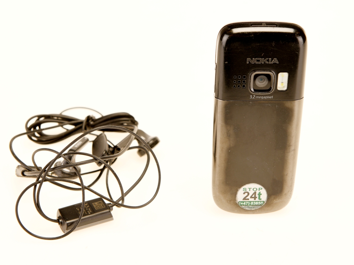 Svart mobilteleton av modellen NOKIA 6303 med tilhørende hodetelefoner HS-47 i svart.