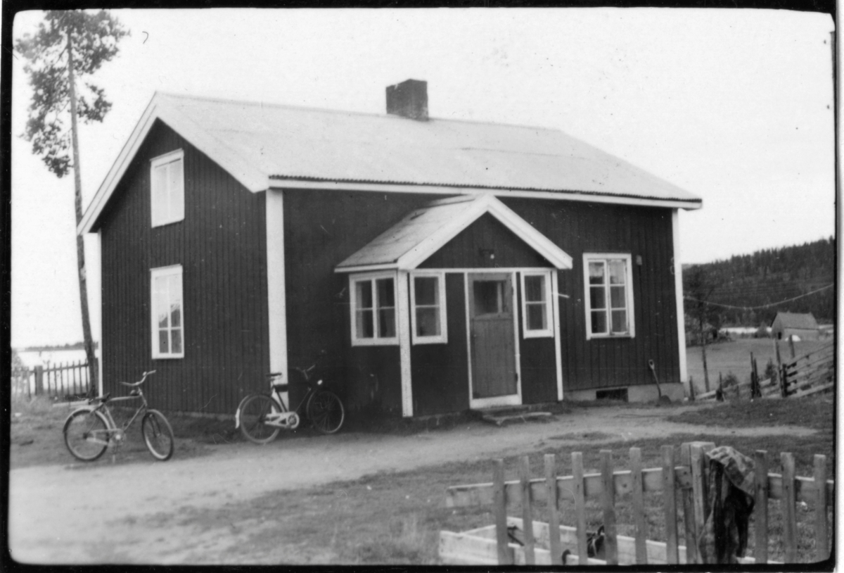 Vägstation AC20, Sorsele, färjvaktarbostaden i Stennäset. Bostadshus, färjvaktarens bostad. Cyklar framför byggnaden. Staket runt byggnaden. Färjeläget i bakgrunden.
