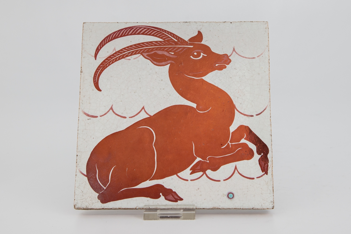Flis med dyremotiv i rød lusterglasur som avbilder en antilope.