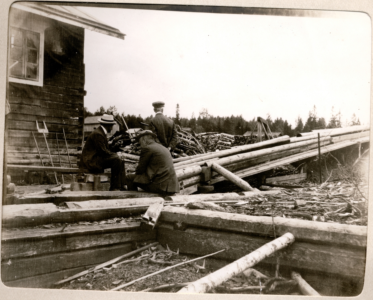 Tre menn på et sagbruk i Finland. Sittende er grosserer Th. Schjelderup og  disponent Gullichsen W. Gutzeit & Co. Fotografert juli 1907. 