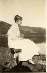 Evelyn Egeberg sitter på en benk ved Lærdalselvi med en revo