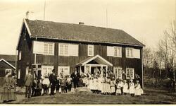 Festkledde barn og voksne samlet 17. mai 1917 foran stort vå