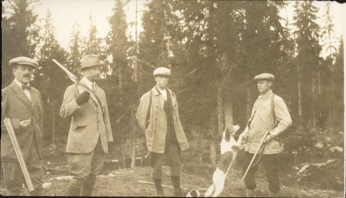 Fire menn på  skogsfugljakt hos Fritz Treschow på Slemdal i Oslo. Fra venstre antagelig Fritz Treschow, Westye P. Egeberg, Fr. Cederfelt og Jæger Petersen med hund. Fotografert august 1922.