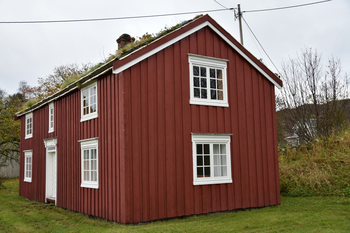 Laftet bygning med tømmermannskledning. Rødmalt med hvit kontrastfarge på omramminger.