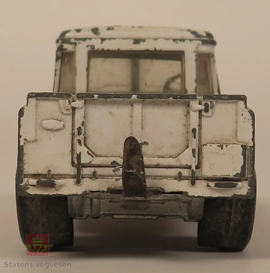 Hovedsakelig hvit og sekundært rød Land Rover modell. Den er laget av metall og mangler en kran på lasteplanet og varsellys på taket. Skala 1:43