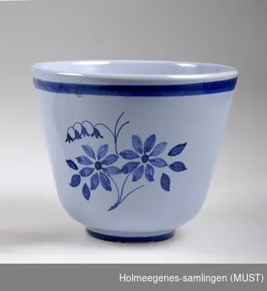 Smal mindre vase i trompettform. Laget av keramikk med tykk glasur i blått og sort på utsiden, sort på innsiden. Produsert ved Gwenni Pottery, sannsynlig engelsk.